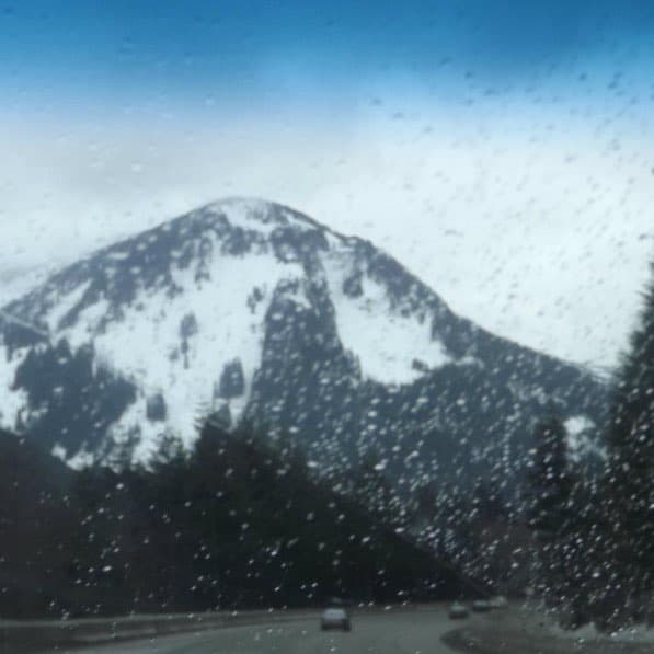 Snow-covered mountain seen through a rain-speckled window.